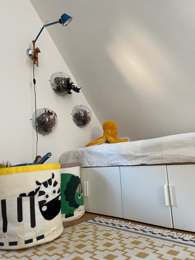 Nach Umsetzung Ein gemütliches Kinderzimmer mit bunten Aufbewahrungskörben und einem Spielzeug auf dem Bett.
