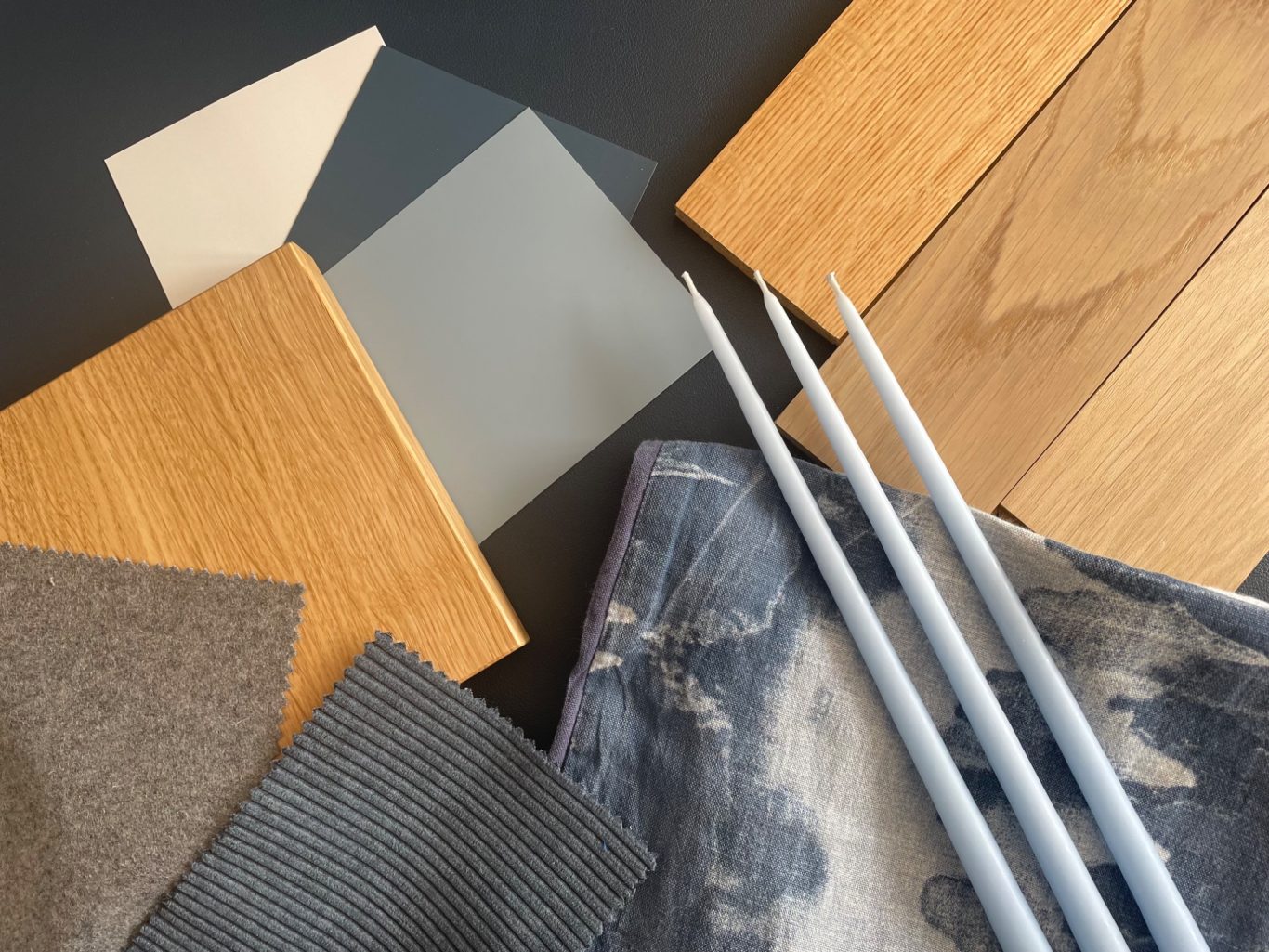 Holz- und Stoffproben in verschiedenen Farben, kombiniert mit Stricknadeln.