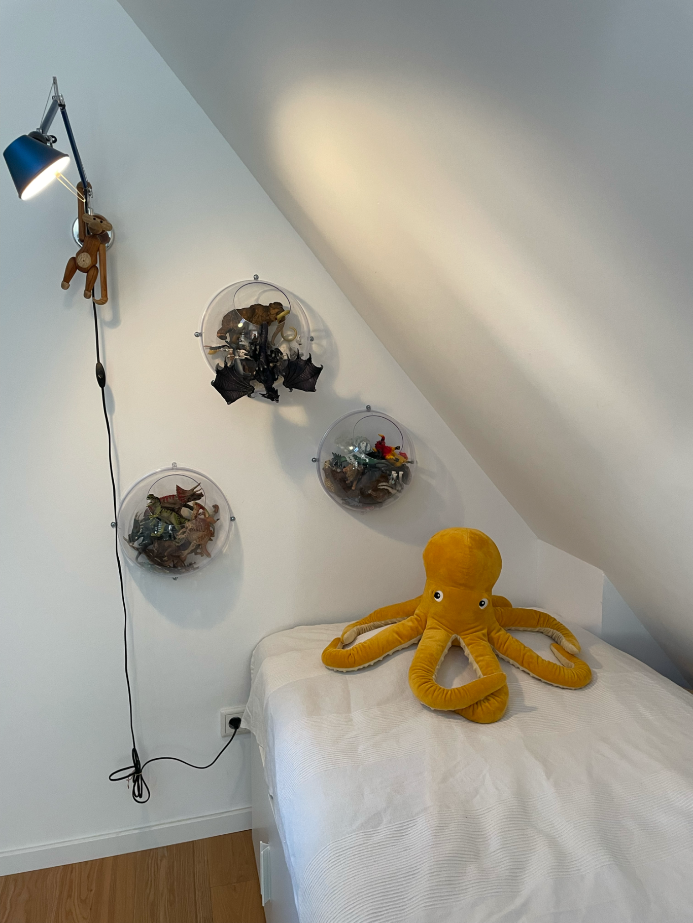 Gelbes Plüsch-Oktopus auf einem Bett, dekorierte Wand mit transparenten Aufbewahrungskörben.