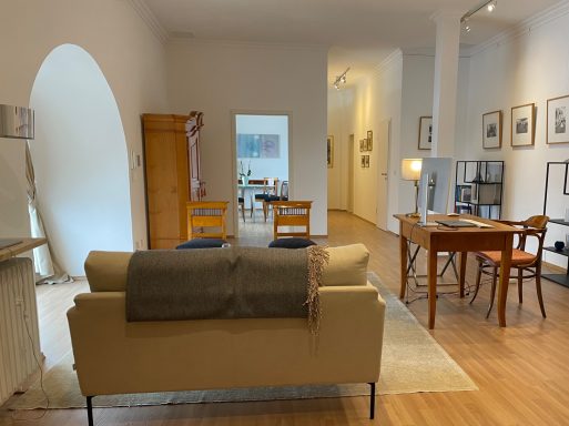 Blick in hellen Büroraum mit Holzfußboden, Tisch, Stühlen und Sofa